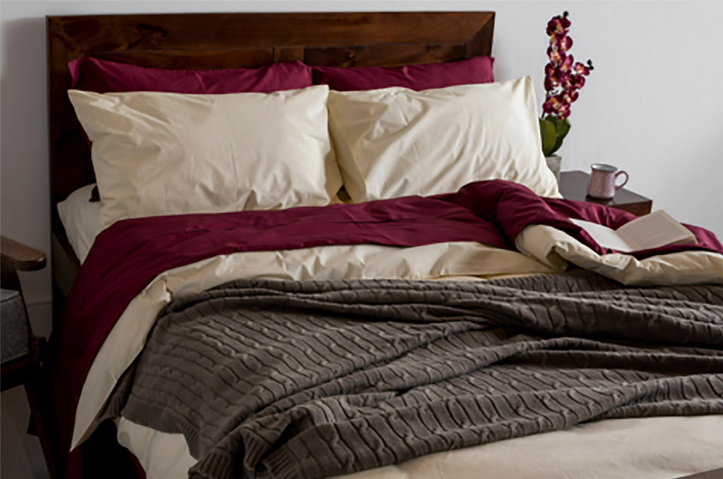Warm bedroom setup featuring premium Pizuna bedding in burgundy, cream, and grey tones